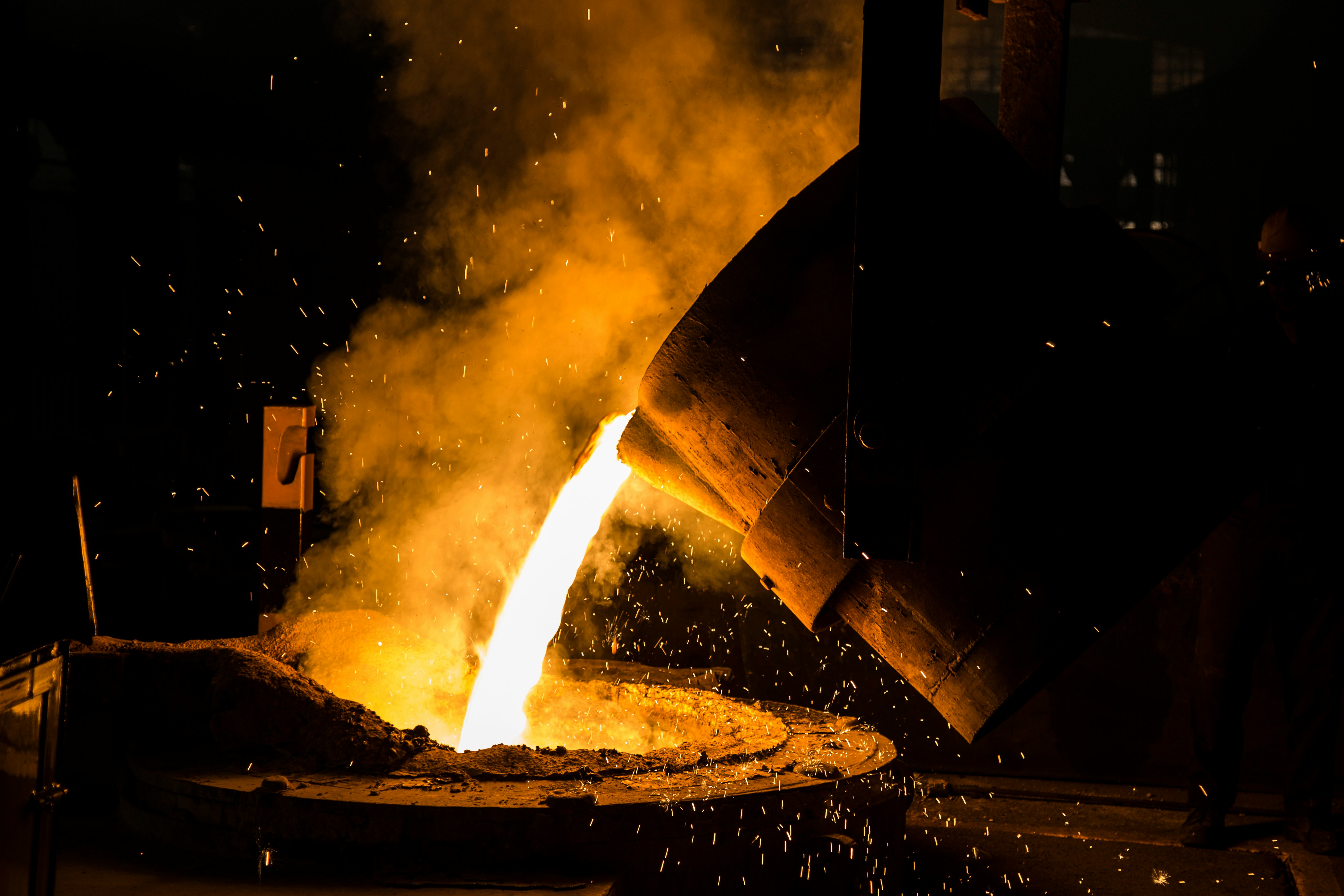 Molten metal pouring from a foundry ladle, sparks flying